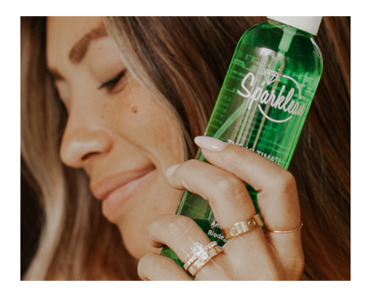 Woman holding a green spray bottle labeled 'Sparklean' with a blurred background